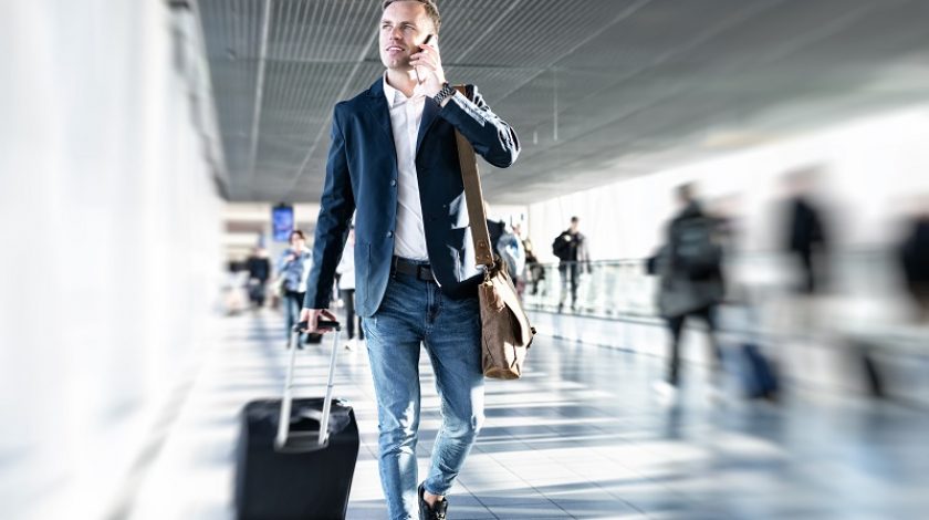 Businessman talking on phone and rushing in airport, blurred background