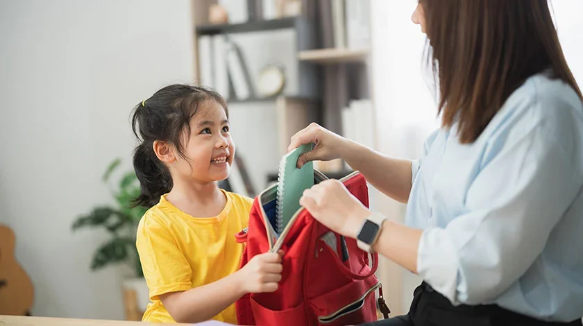 Photo of a woman handing a child a bag
