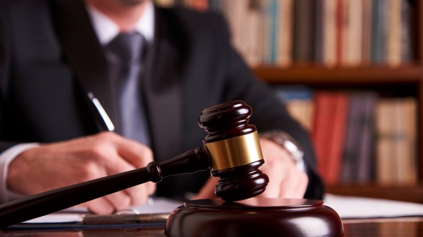 Judge or lawyer working with agreement in courtroom theme. Justice and Law concept with judge's gavel on wooden table with law books on background