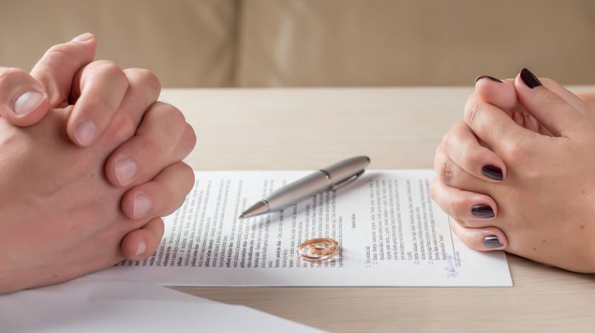hands of wife and husband signing divorce documents or premarital agreement