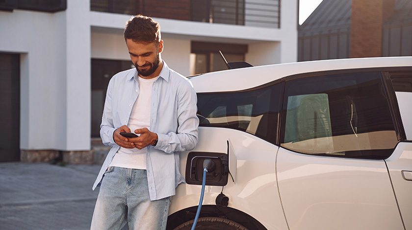A man leans on the side of an electric vehicle