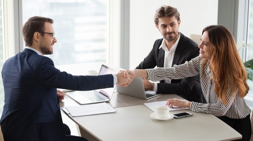 Businessman handshaking businesswoman making deal finishing group negotiations, satisfied smiling business partners conclude contract agreement shake hands expressing respect thank for group meeting