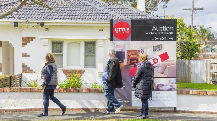 Melbourne, Australia - August 30, 2015: People walking past an auction sign on display outside a house in Melbourne during daytime. The property market in Melbourne is one of the strongest among other capital cities in Australia.