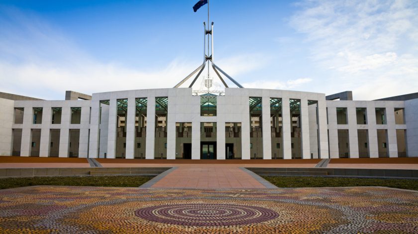 This is the Australian Parliament House in Canberra. It is white with landscaped lawns and a flag in the middle