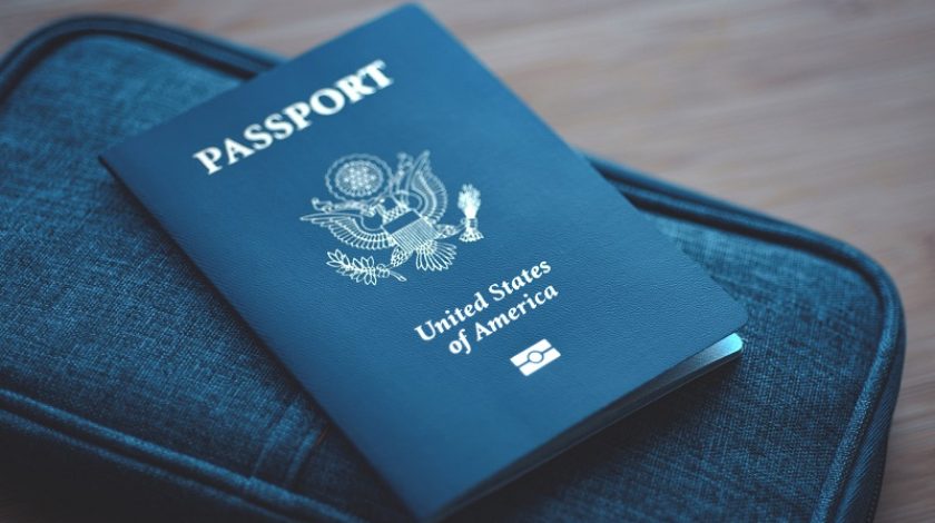Passport of USA (United States of America) on blue travel wallet, wooden background. Close up.